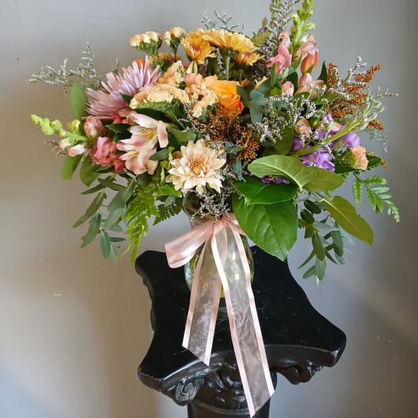 Mixed bouquet in a glass vase with a pink ribbon