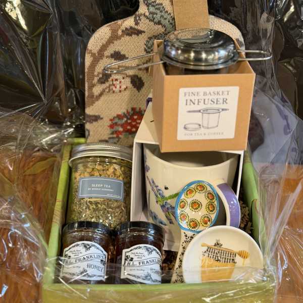Gift basket with tea, honey, mugs, and a decorative bottle-shaped container