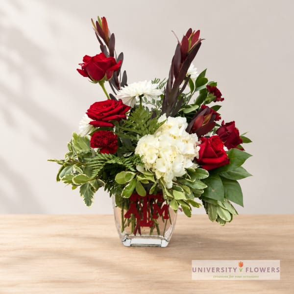 Red roses and white flowers arranged in a clear glass vase