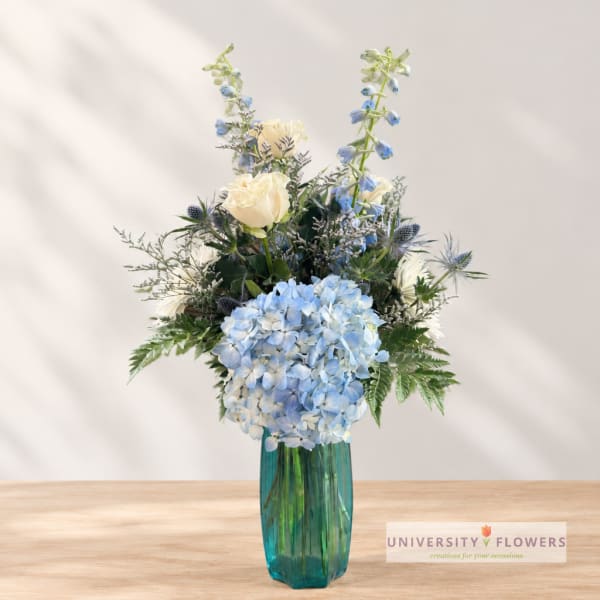 Blue hydrangeas and white roses in a teal glass vase