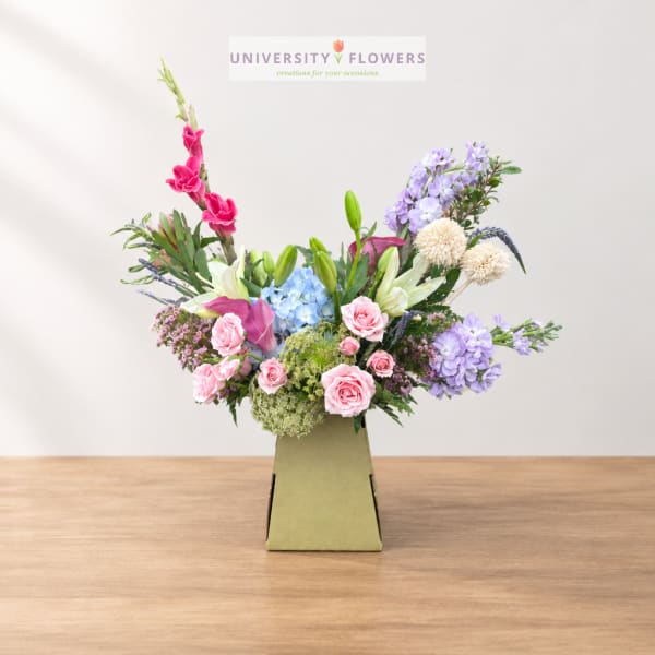 Mixed bouquet in a green box with pink, purple, blue, and white flowers