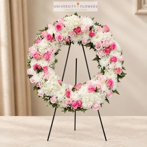 Pink and white floral wreath on a black stand