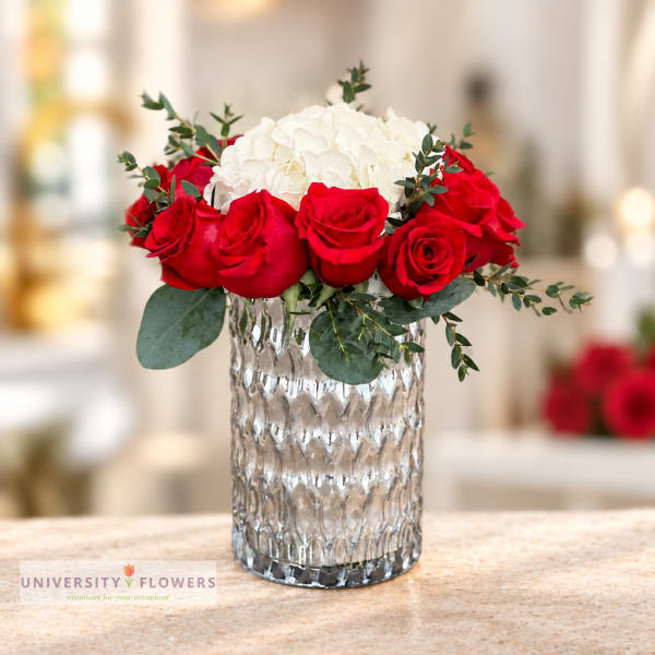 Red roses and white hydrangeas in a textured glass vase