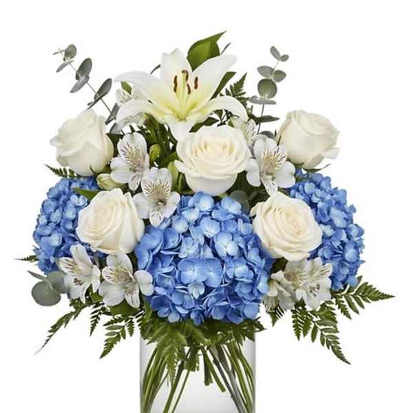 Blue hydrangeas and white roses in a clear glass vase