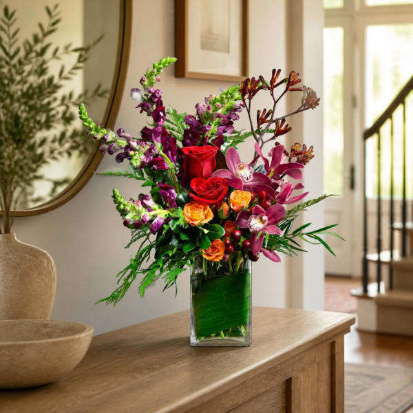 Mixed bouquet of roses and orchids in a clear glass vase