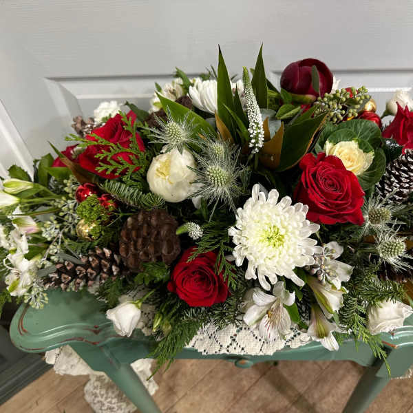 Red and white floral arrangement with pinecones in a low container