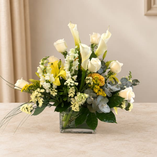 White roses and calla lilies in a square glass vase