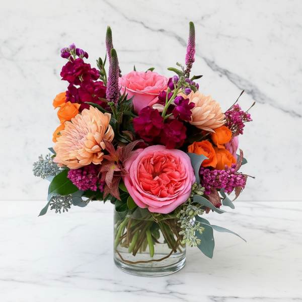 Pink and orange mixed flower arrangement in a clear glass vase