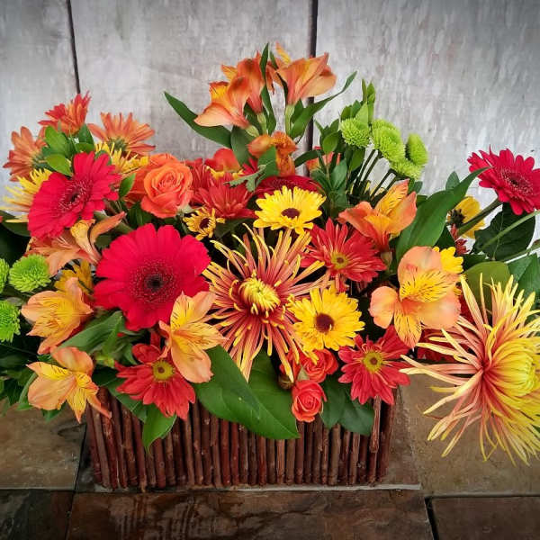 Bright mixed flower arrangement in a rectangular wooden basket