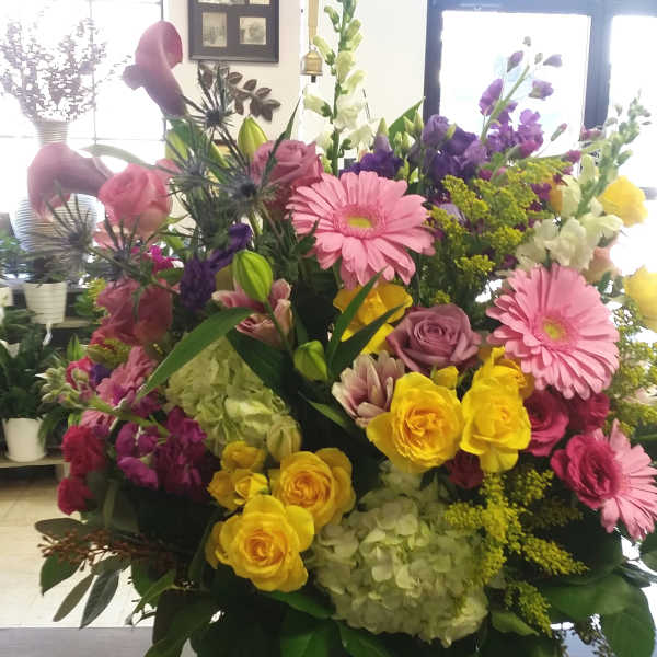 Large mixed bouquet in a black vase with pink, yellow, purple, and white flowers