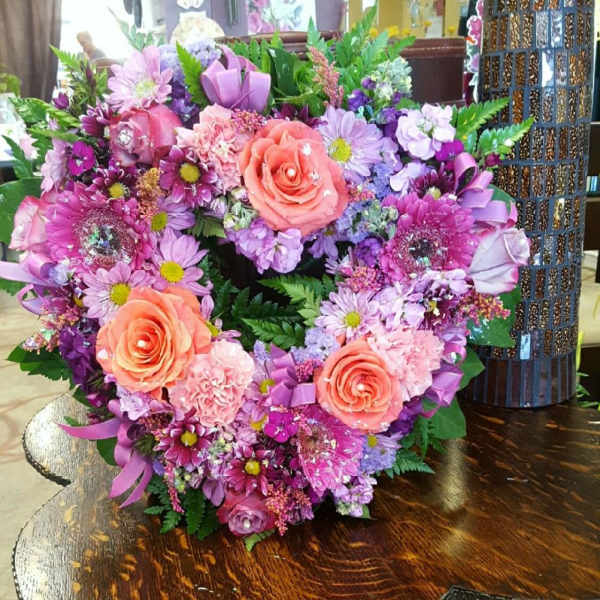 Heart-shaped bouquet of pink and purple flowers with peach roses