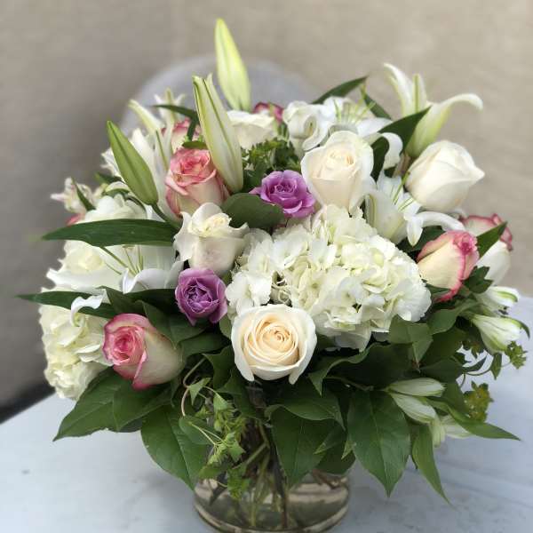 Mixed bouquet of white and pink roses with lilies in a glass vase
