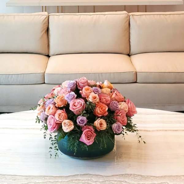 Pink and lavender rose arrangement in a low round container