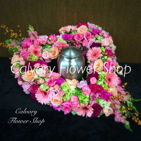 Pink and peach floral wreath around a silver urn