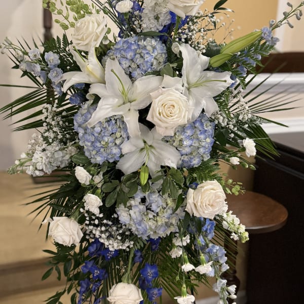 Tall blue and white floral spray with roses, lilies, and hydrangeas
