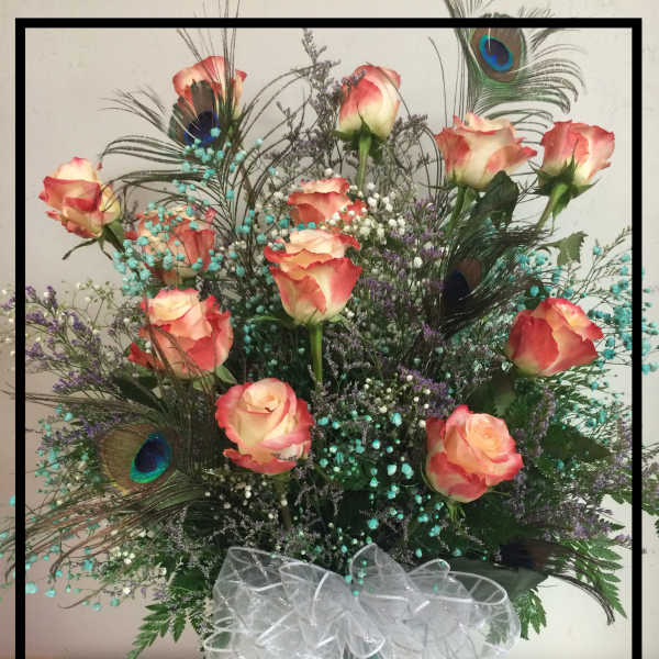 Tall bouquet of peach roses with peacock feathers in a vase