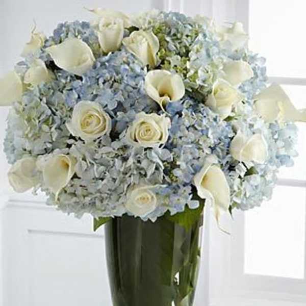 White roses and calla lilies in a tall glass vase
