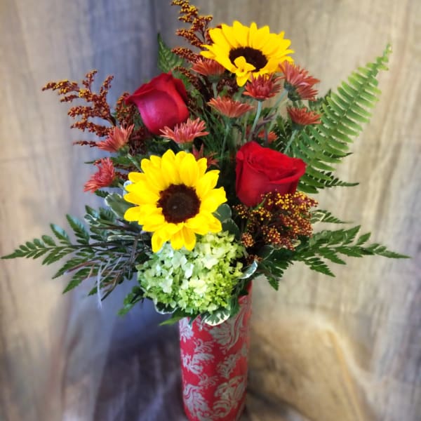 Bouquet of sunflowers, red roses, and green hydrangea in a red vase