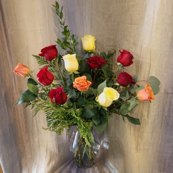 Bouquet of red, yellow, and peach roses in a clear glass vase