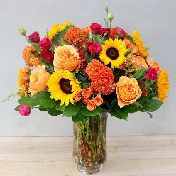 Mixed bouquet of roses and sunflowers in a clear glass vase