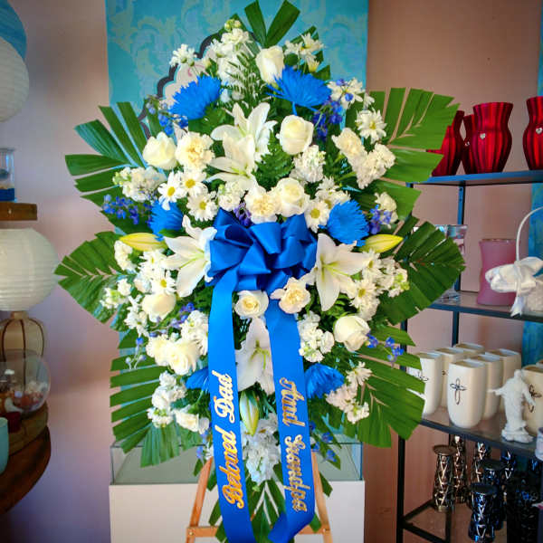 Large white and blue floral standing spray with a blue ribbon bow