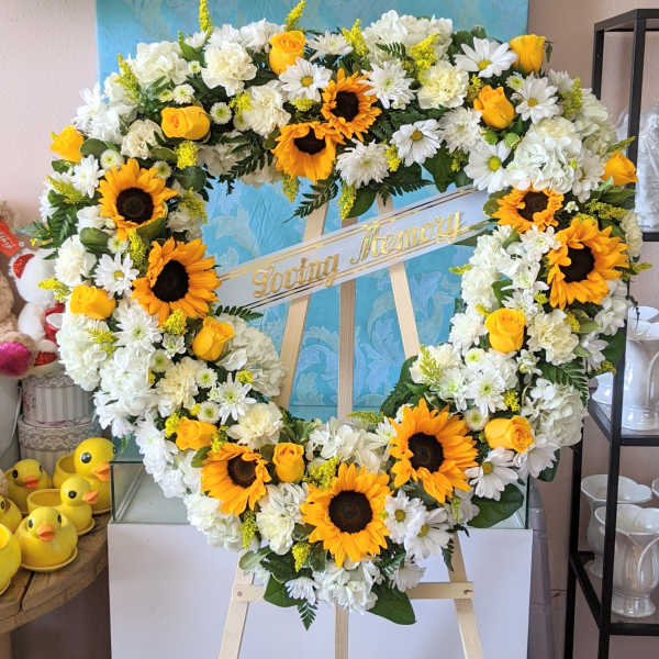 Heart-shaped floral wreath with sunflowers, white daisies, and yellow roses