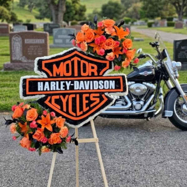 Orange floral tribute on an easel with a Harley-Davidson sign