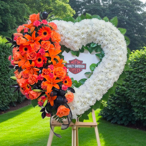Heart-shaped floral tribute with orange and white flowers on an easel