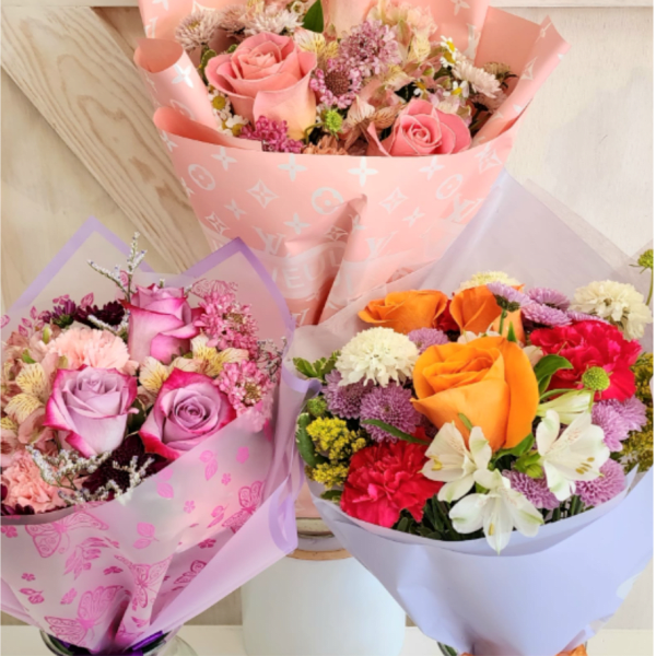 Three mixed flower bouquets in pink, lavender, and white wrapping