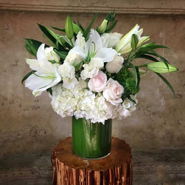 White lilies and roses arranged in a green vase