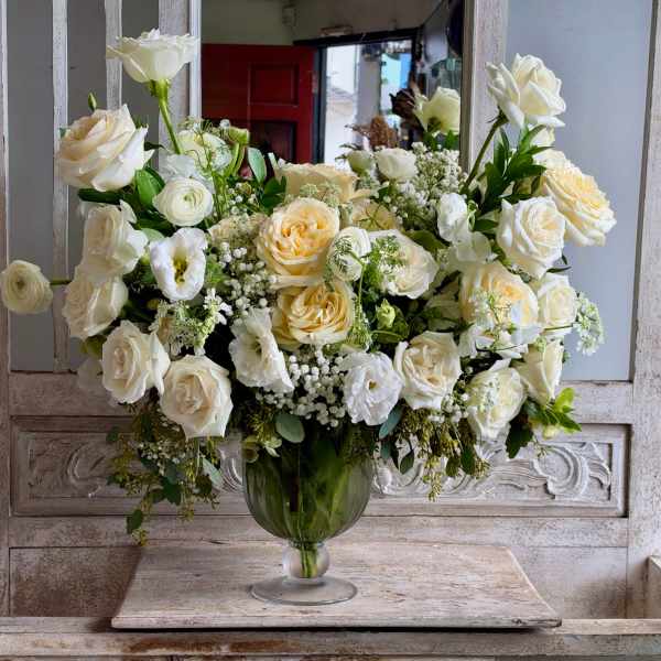 White rose arrangement in a green glass vase