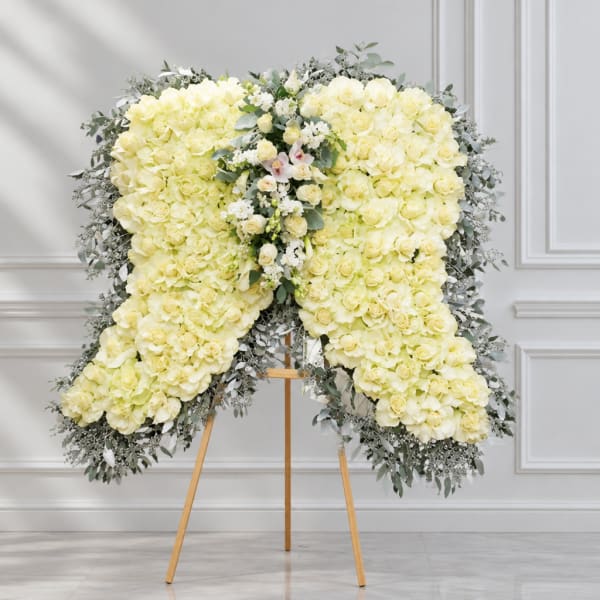 Large white rose funeral spray on an easel with greenery