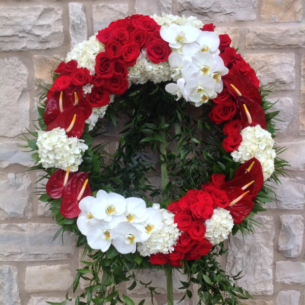 Circular funeral wreath of red roses, white orchids, and white hydrangeas
