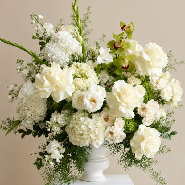 White floral arrangement in a white vase with green accents
