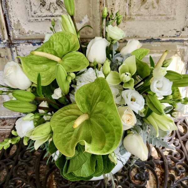 White and green floral arrangement with anthuriums, roses, and lilies in a vase