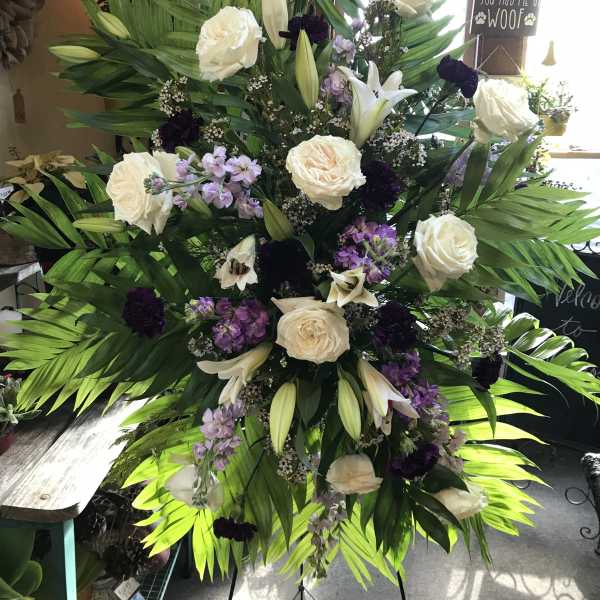 Tall standing floral spray with white roses, lilies, and purple accents