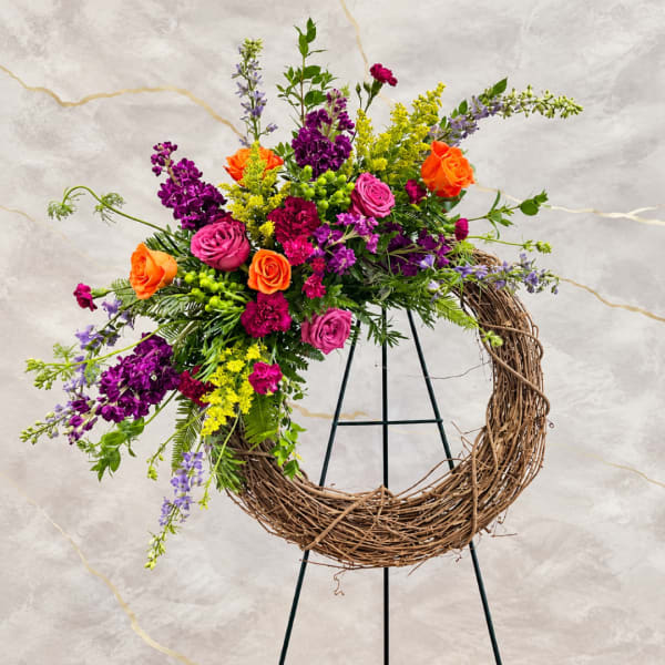 Colorful floral wreath with roses and purple blooms on a stand