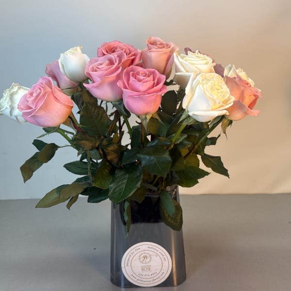 Pink and white roses arranged in a dark vase