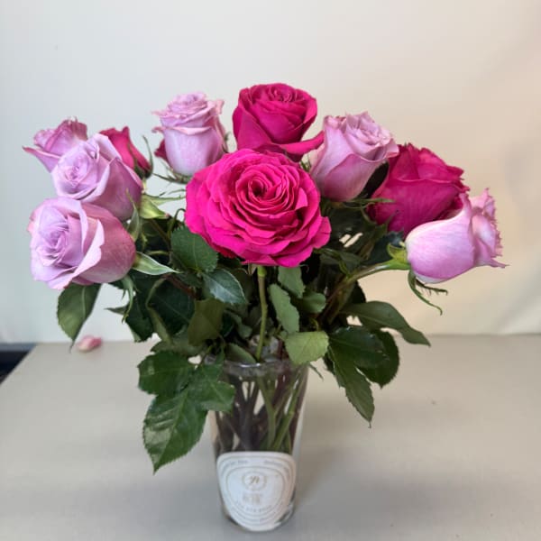Pink and lavender roses arranged in a clear glass vase