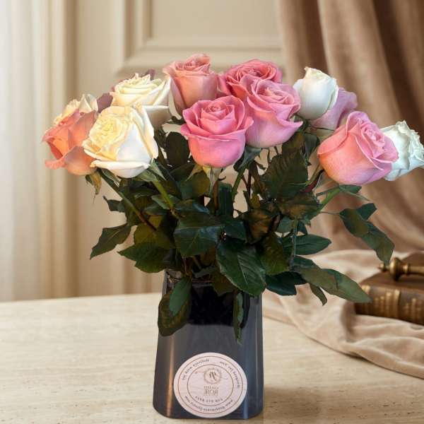 Pink and white roses arranged in a dark vase on a table