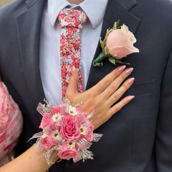 Pink rose corsage and boutonniere on a dark suit with a floral tie
