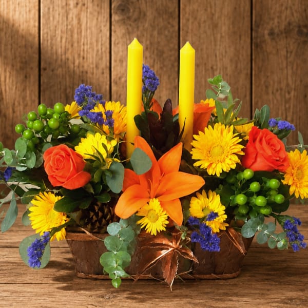 Orange and yellow floral centerpiece with two yellow candles