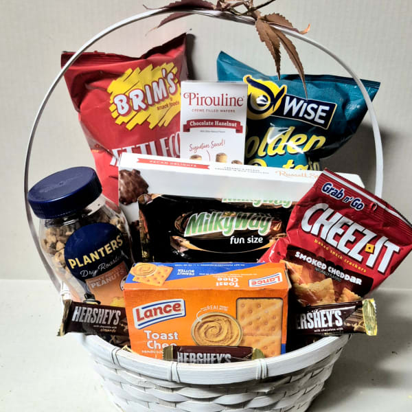 Gift basket filled with assorted snack bags, cookies, and candy in a white basket