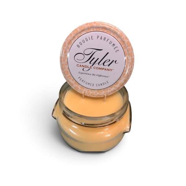 A scented candle in a glass jar with a round lid label