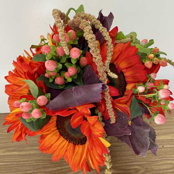 Bouquet of orange sunflowers with pink berries and dark purple foliage