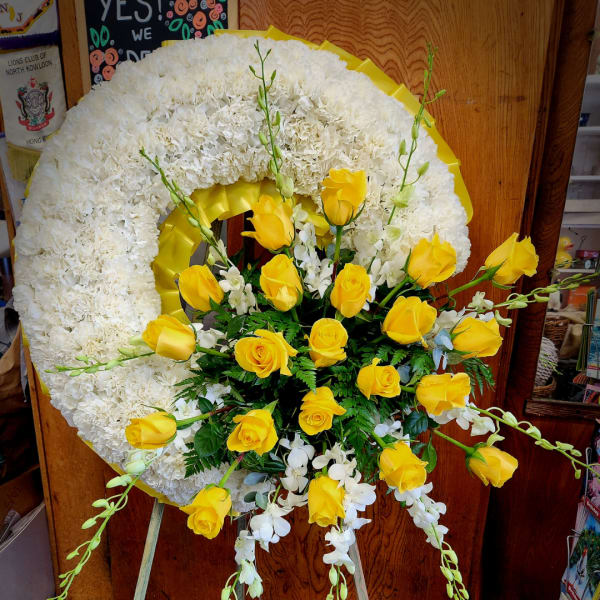 White floral wreath with yellow roses and white orchids on an easel