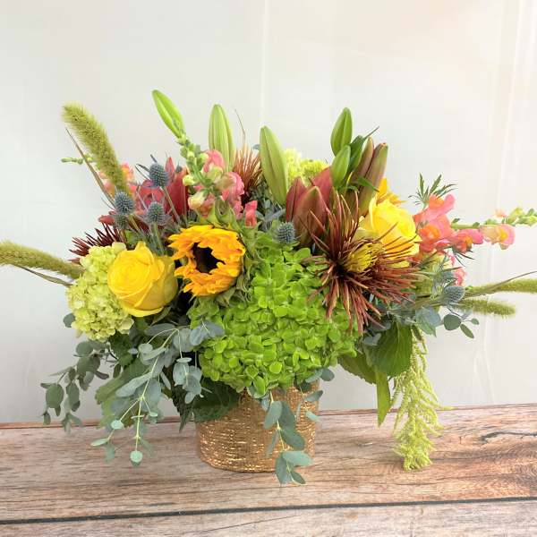 Bright mixed bouquet in a gold vase with yellow and pink blooms