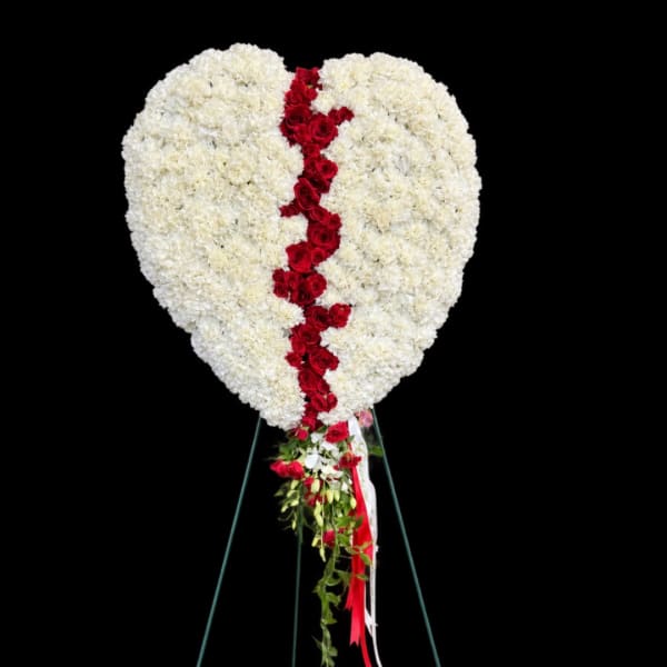 Heart-shaped white floral spray with a red rose stripe on a stand
