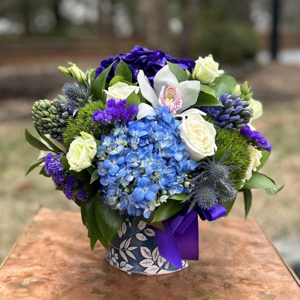 Blue hydrangeas, white roses, and purple flowers in a patterned vase