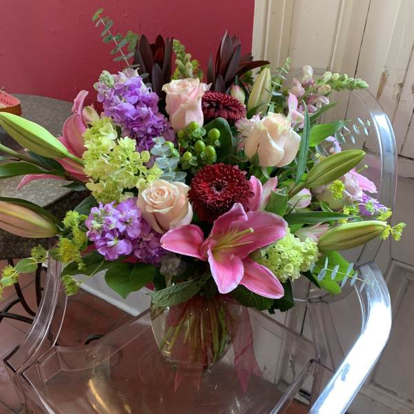 Bouquet of pink lilies, roses, and purple flowers in a glass vase
